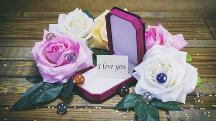 Honeymoon gift box and flowers on wooden background, a note on t