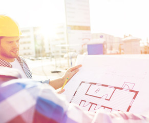 Canvas Print - close up of builders with blueprint at building