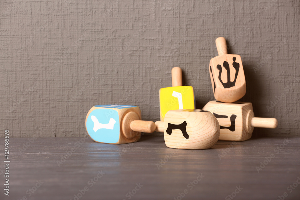 Dreidels for Hanukkah on wooden table against grey textured wall