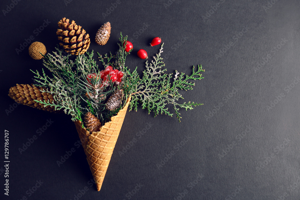 Waffle cone with composition of coniferous branches, berries and strobiles on dark background
