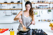 Young Woman Frying Onion Into The Pan In The Kitchen.
