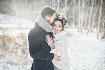 The bride and groom hugging. Beautiful couple walking in the Park in winter.