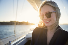 Australia, New South Wales, Sydney Harbor, Smiling Woman In Sunglasses On Boat At Sunset