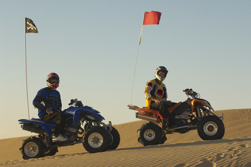 Wall Mural - Portrait of young men with helmets sitting on quad bikes in the desert