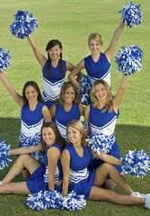 Wall Mural - Portrait of beautiful cheerleaders holding pompoms on field