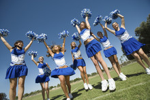 Group Of Excited Young Cheerleaders Cheering On Field