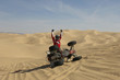 Male quad racer cheering tipped-over quad bike in desert