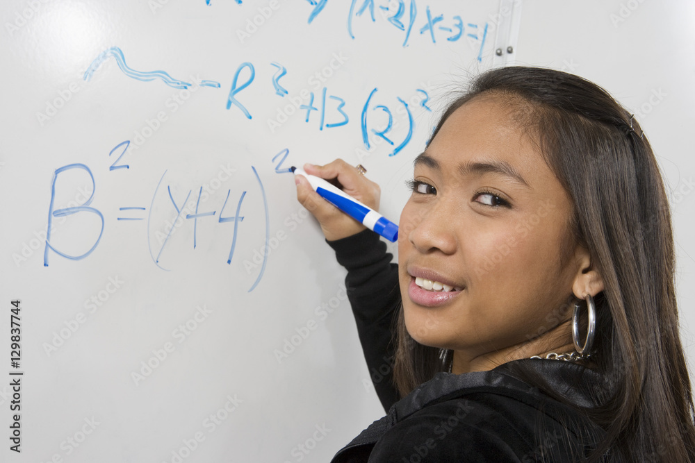 Portrait of an Asian student solving mathematics problem on white board ...