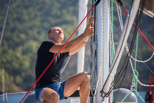 Fotomural Yachtsman pulls the rope controlling the sail on sailing boat.