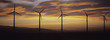 Silhouette wind turbines in a row against cloudy sky at sunset