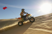 Side View Of A Man Riding Quad Bike In Desert On A Sunny Day