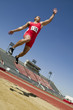 © moodboard - Full length of a male athlete doing a long jump into a sandpit