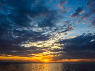 Wall Mural - Sunset sky with gold background at te sky line on the sea