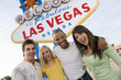 Portrait of happy friends standing together against 'Welcome To Las Vegas' sign