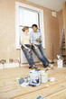 Full length of couple holding coffee mugs while looking at each other with paint cans in foreground