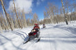 Two couples riding on two snowmobiles along the snowy track