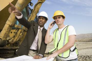 Architect pointing towards something while construction worker on call