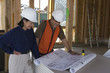 © MDBPIXS - Female engineer and co-worker working over blueprint at construction site