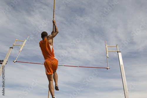 Plakat Niskiego kąta widok męska atleta wykonuje słup kryptę przeciw niebu