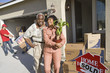Cheerful African American couple with belongings moving into a new house