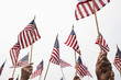 © moodboard - Hands raising American flags against clear sky