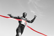 © moodboard - Low angle view of an African American male runner crossing finish line against blue sky