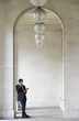 © MDBPIXS - Full length of young businessman using cell phone while leaning in archway