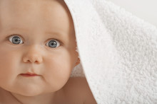 Closeup Portrait Of Cute Baby With Blue Eyes Under Towel
