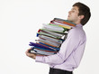 Male office worker carrying heavy binders against white background