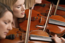 Closeup Of Three Women Playing Violins In Musical Group