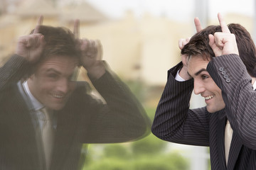 Wall Mural - Reflection of playful young businessman making a funny face