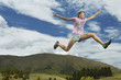 Low angle view of a young woman leaping on rural landscape