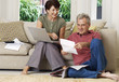 © MDBPIXS - Middle aged couple looking at bill and laptop in the living room