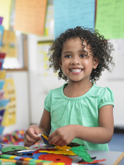 portrait of smiling little girl assembling puzzles in classroom