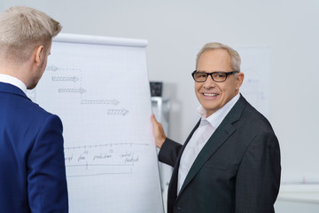 Wall Mural - zufriedener älterer geschäftsmann steht mit einem mitarbeiter am flipchart