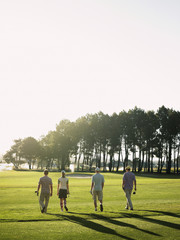 Rear view of young golfers walking on golf course