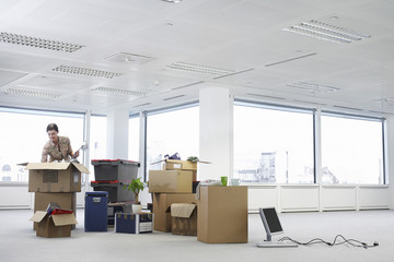 Young businesswoman unpacking cartons in an empty office space