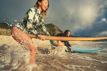 Two Surfer Girls Standing In Water Wave Splashes Surrounded By Drops Ready To Start Surfing With Surfboards