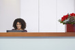 Afro American receptionist using computer behind reception desk