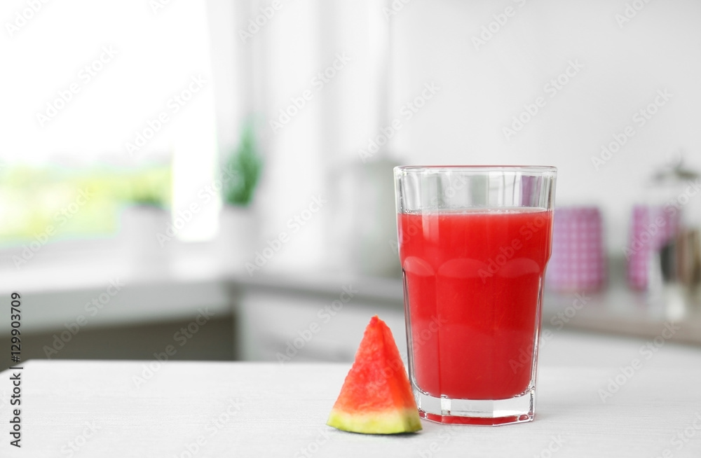 Glass with fresh smoothie and watermelon slice on kitchen table
