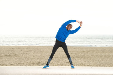 Wall Mural - african american man stretching muscles at the beach