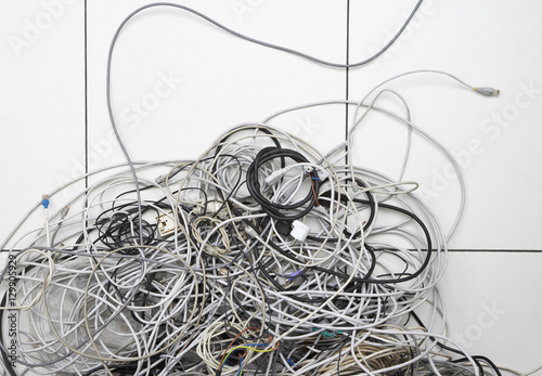 Fotografie, Obraz Closeup of tangled computer wires on tiled floor in office