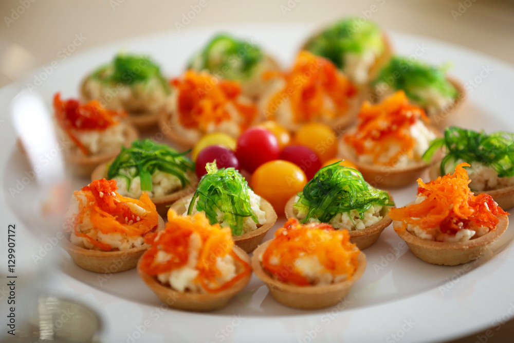 Plate with tasty tartlets on wooden table, close up view