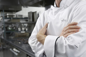 Wall Mural - Closeup midsection of a male chef with arms crossed in kitchen