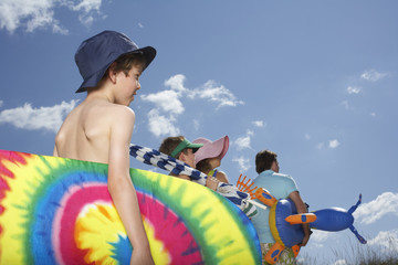 Rear view of parents with sons carrying beach accessories