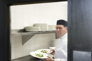 Wall Mural - Portrait of a male chef holding food plates in the kitchen