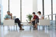 © MDBPIXS - Full length side view of four business people sitting in modern waiting room at office