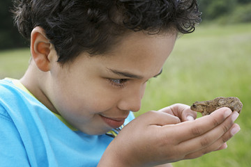 Closeup of young boy observing toad outdoors