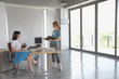 © MDBPIXS - Full length side view of two female executives talking at desk in empty office