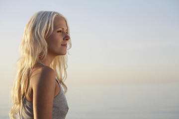 Side view of beautiful young woman standing on beach